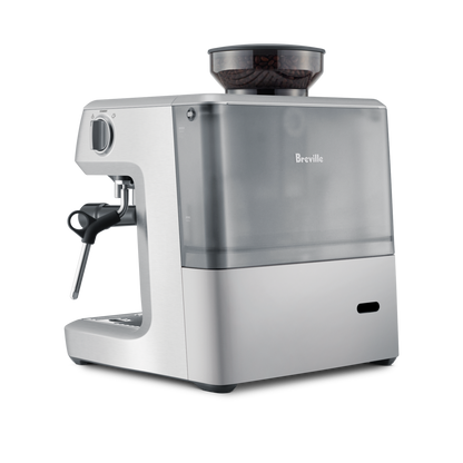 The Breville - The Barista Express™ is a silver espresso machine with a transparent water reservoir and bean hopper on top, built-in grinder, steam wand, and sleek modern design.