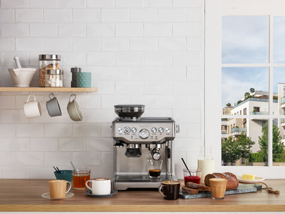 A Breville - The Barista Express™ espresso machine with a built-in grinder sits on the counter, surrounded by coffee cups.